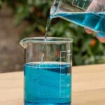 pouring blue liquid curezin into another glass